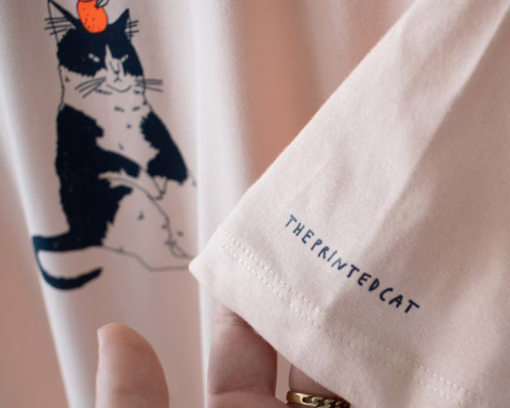 Orange Cat t-shirt | Hand screen printed illustration of a cat balancing oranges on misty pink organic cotton tee with navy and orange