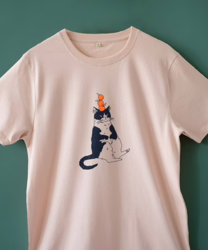 Orange Cat t-shirt | Hand screen printed illustration of a cat balancing oranges on misty pink organic cotton tee with navy and orange