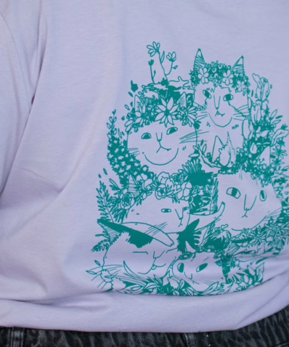 Summer Bouquet T-Shirt | Hand screen printed illustration of 7 cats with flowercrowns and other plants in green on lilac organic cotton tee